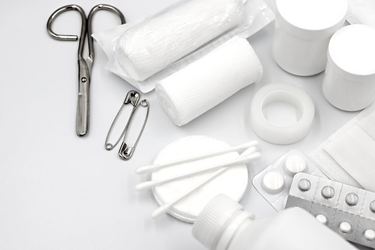 A detailed flat lay of essential first aid supplies including bandages, scissors, and pills.